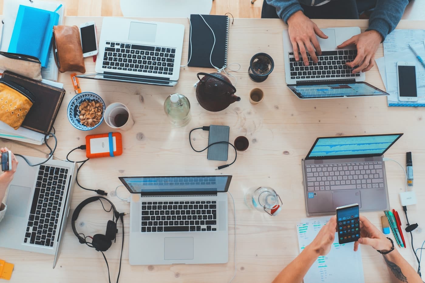 A busy workspace of laptops, notes, and coffee mid-project